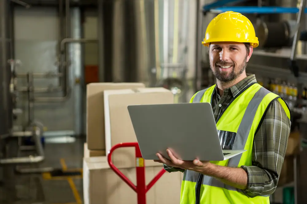 smiling-male-worker-using-laptop-distribution-warehouse